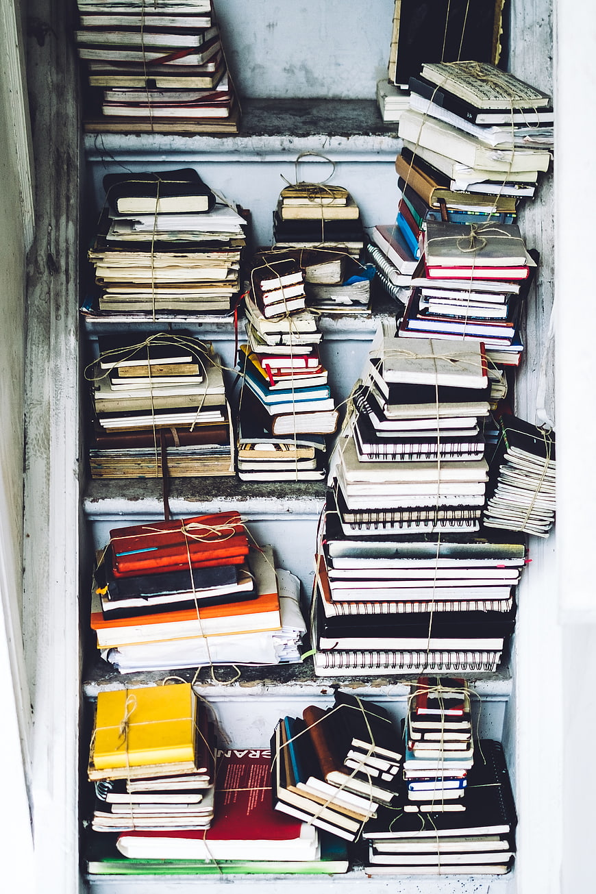 Stacks of vintage notebooks and books tied with twine on shelves
