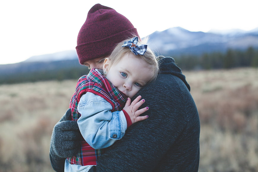 Mother holding toddler daughter in mountain field