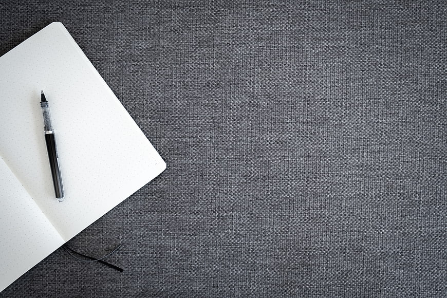 Minimalist notebook and pen on textured gray background