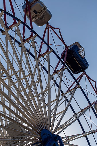 Low angle view of vintage ferris wheel against blue sky
