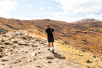 Man hiking on rocky mountain trail in autumn