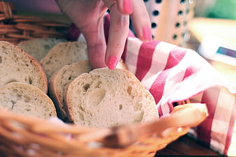 Hand Reaching for Fresh Sliced Bread in Wicker Basket