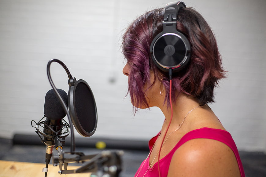 Woman with purple hair recording in studio with microphone