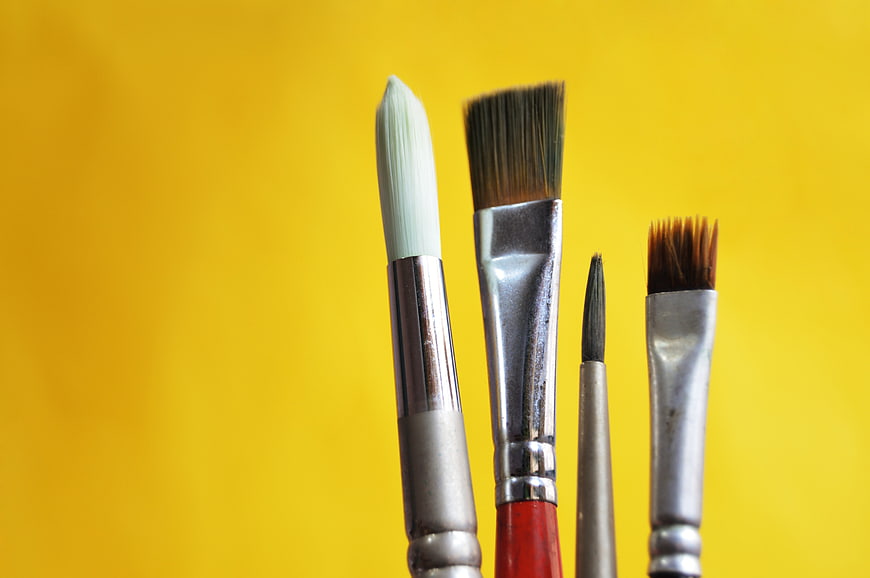 Close-up of paint brushes on yellow background