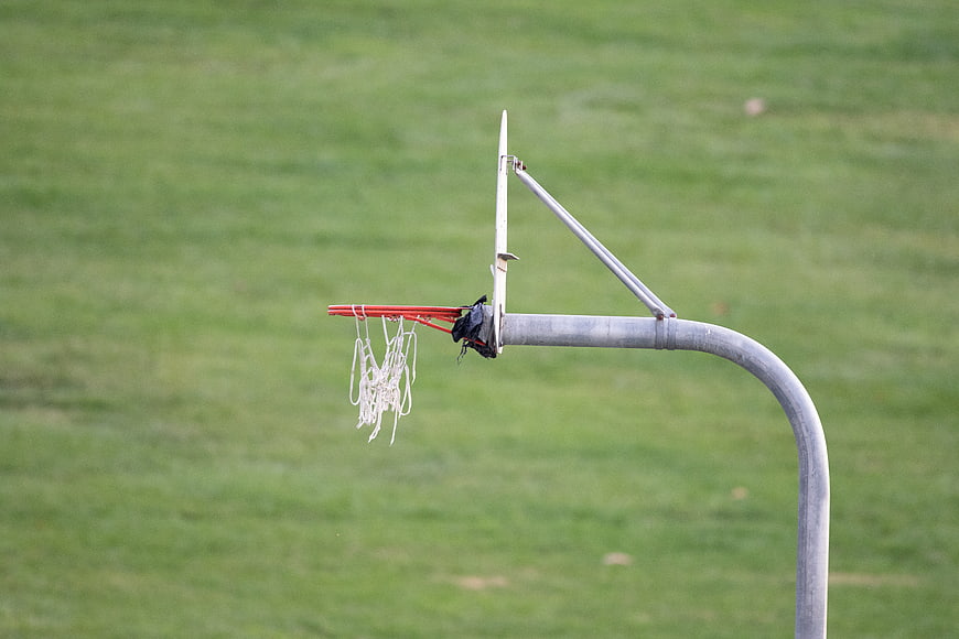 Outdoor basketball hoop with net on green grass field
