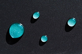Glittering teal liquid drops on dark textured background