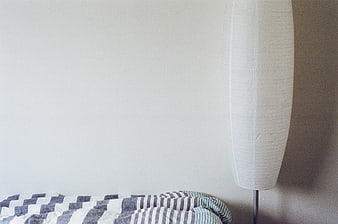 Minimalist Bedroom Corner with Striped Bedding and Paper Lamp