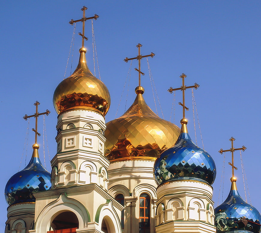 Golden and blue onion domes of an Orthodox church against blue sky