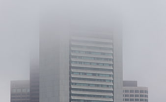 Modern skyscraper obscured by thick fog in city