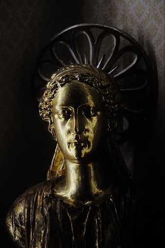 Golden religious statue bust with dramatic lighting