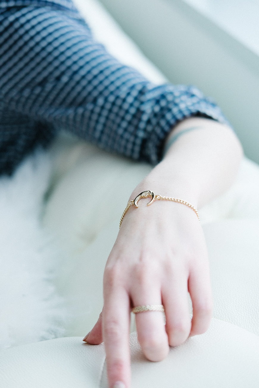Close-up of woman's hand wearing gold jewelry on white leather