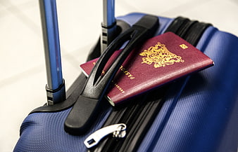 Maroon passports resting on blue travel suitcase