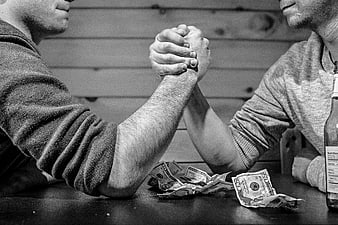 Men arm wrestling with cash on table