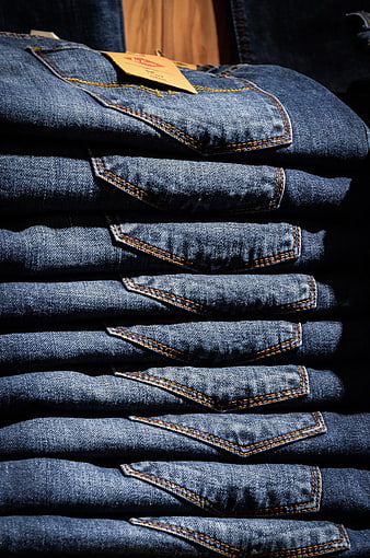 Stack of folded blue denim jeans with orange stitching