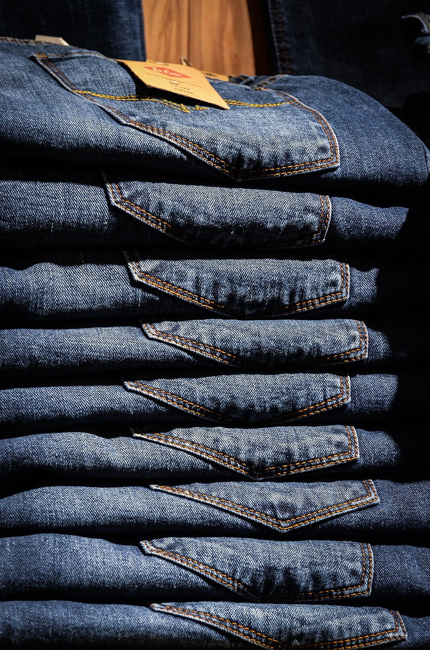 Stack of folded blue denim jeans with orange stitching
