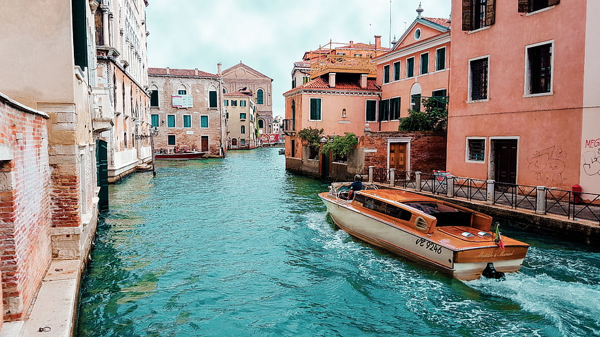 Orange wooden water taxi speeding through Venice canal