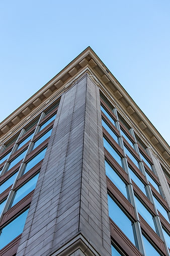 Low angle view of modern office building corner against blue sky