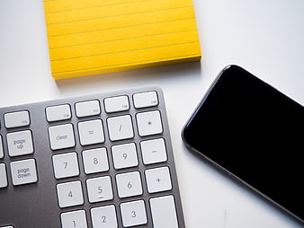 Minimalist workspace with keyboard, smartphone, and yellow sticky notes