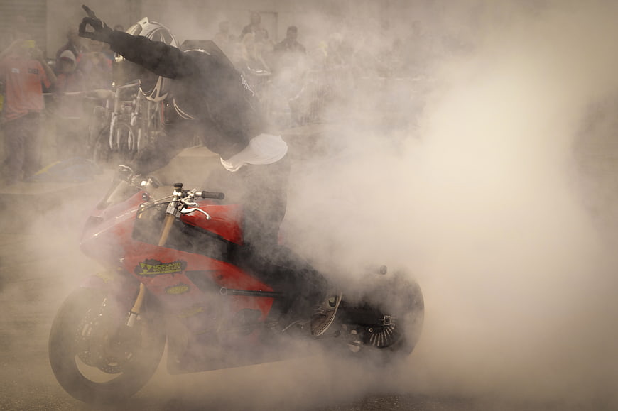 Motorcyclist performing a burnout stunt with heavy smoke