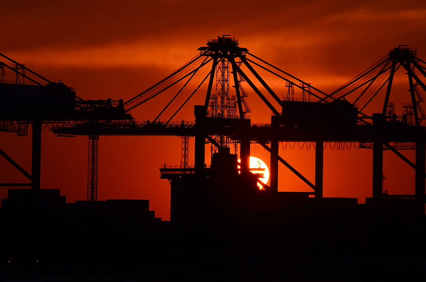 Silhouette of Port Cranes Against Vibrant Orange Sunset