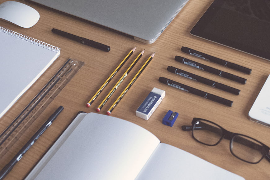 Flat lay of office supplies, laptop, and notebook on wooden desk
