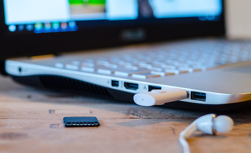 Close-up of laptop side ports with USB drive and earphones