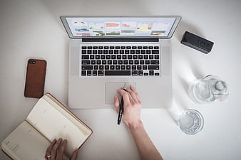 Top view of workspace with laptop, notebook, and water