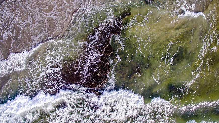 Aerial view of ocean waves crashing on rocky shore