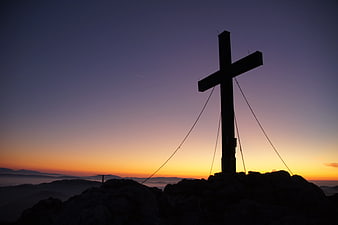 Silhouette of Cross on Mountain Peak at Sunset