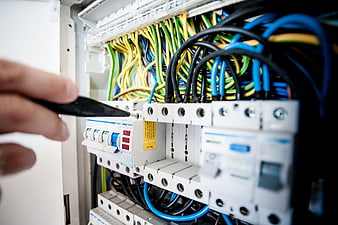 Electrician repairing electrical switchboard with multimeter