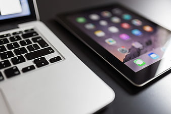Close-up of MacBook and iPad on dark desk