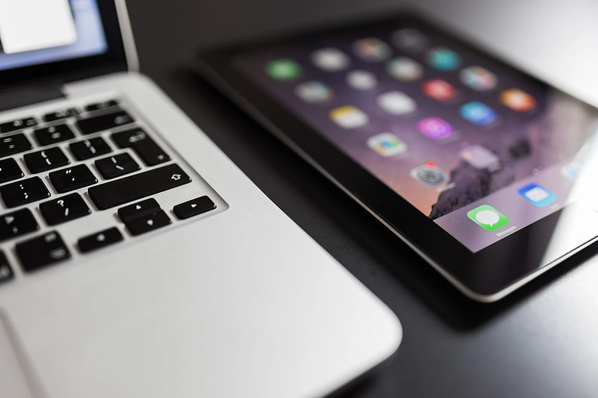 Close-up of MacBook and iPad on dark desk