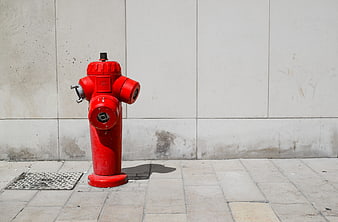 Red fire hydrant on city sidewalk against concrete wall