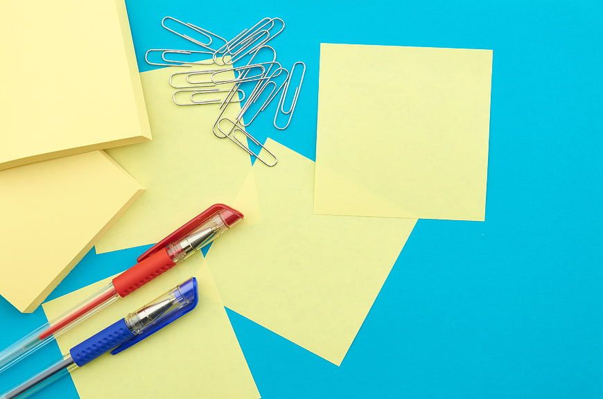 Yellow sticky notes and pens on blue background