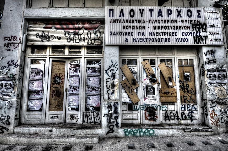 Abandoned Greek Shop Front with Graffiti and Boarded Windows