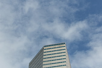 Low angle view of modern office building against cloudy sky
