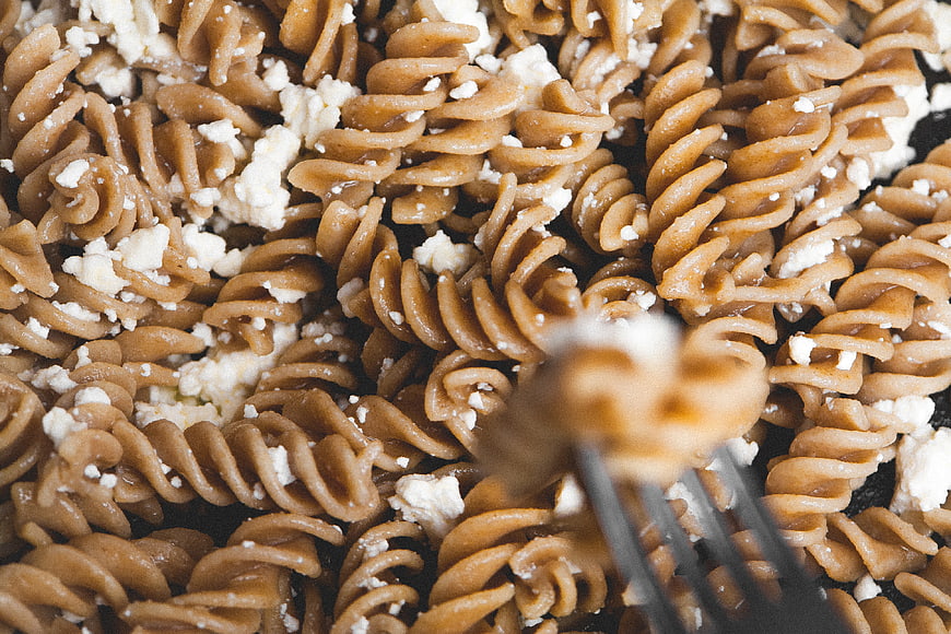 Close-up of whole wheat fusilli pasta with feta cheese and fork