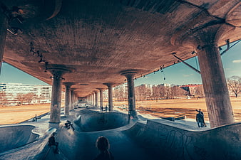 Skateboarders at Urban Concrete Skatepark Under Bridge