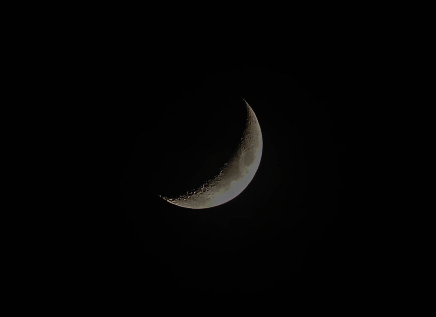 Crescent moon with craters against black night sky