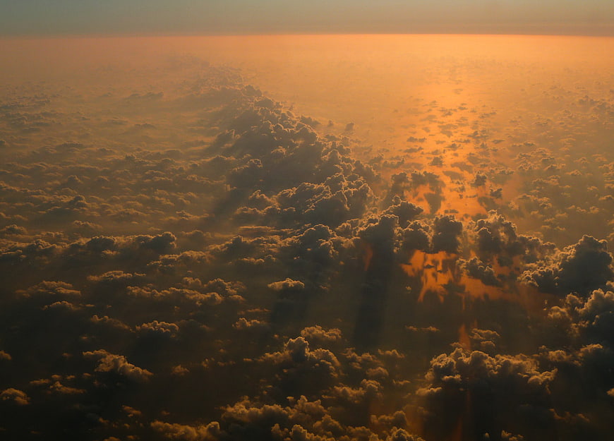 Aerial View of Golden Sunset Clouds from Airplane Window