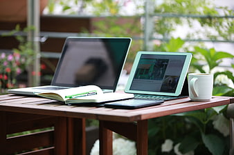 Outdoor workspace with laptop, tablet, and coffee on wooden table
