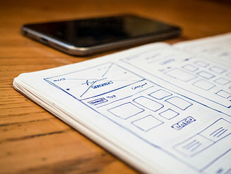 Hand-drawn wireframe sketch on notebook with smartphone