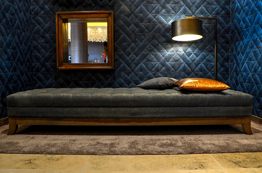 Luxurious blue tufted wall with modern bench and lamp