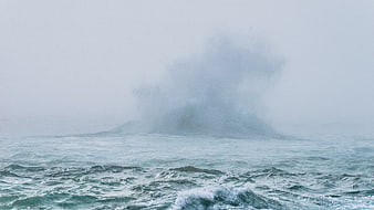 Majestic ocean wave crashing through thick fog and mist