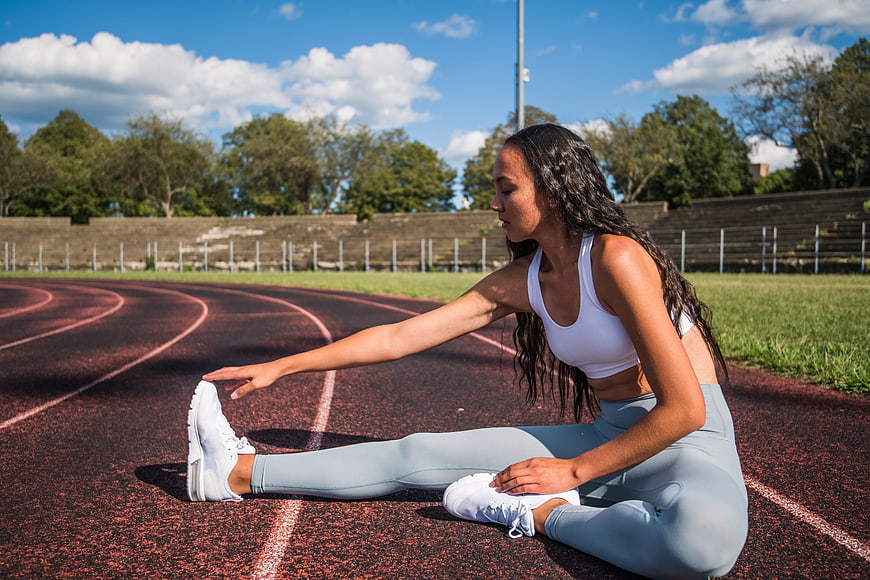 Athletic woman stretching on outdoor running track