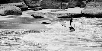 Surfer walking into ocean waves with surfboard