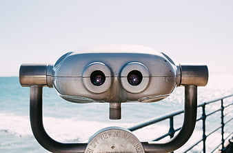 Close-up of silver coin-operated binoculars overlooking the ocean