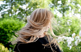 Blonde woman with windblown hair in a green garden