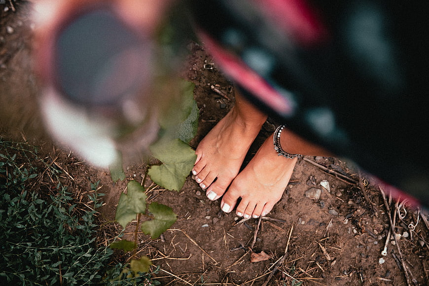 Barefoot woman standing on dirt path in vineyard
