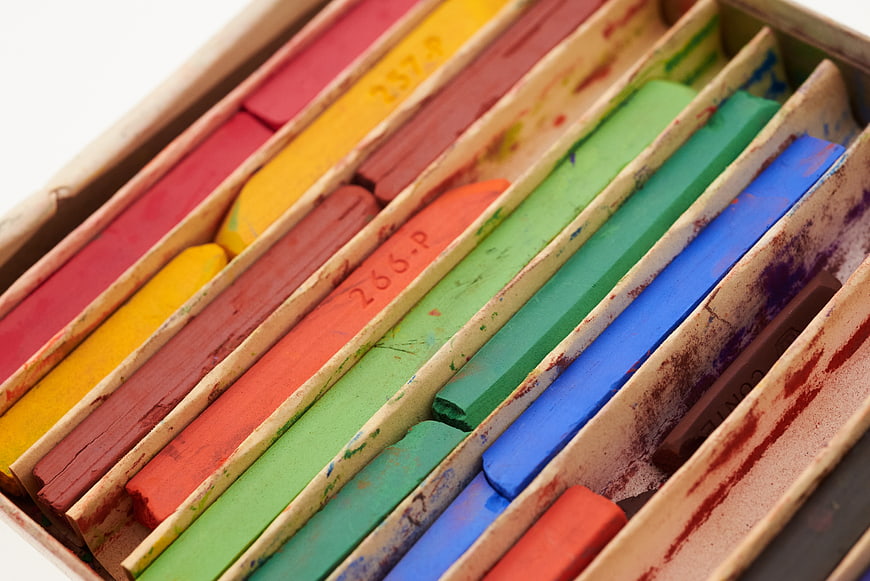 Close-up of colorful pastel chalk sticks in a cardboard box